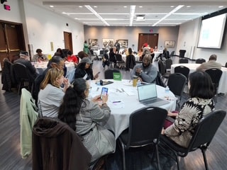 Workshop participants seated at round tables in conference room